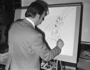 Albert Uderzo mit seiner Figur am Zeichentisch.